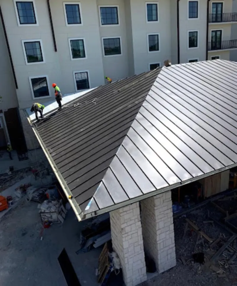 Crew installing standing seam metal roof panels on a commercial project in Highwood